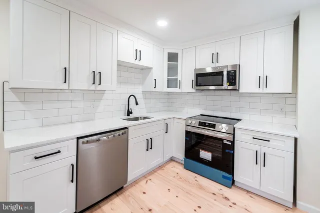 a kitchen with cabinets stainless steel appliances a sink and a stove