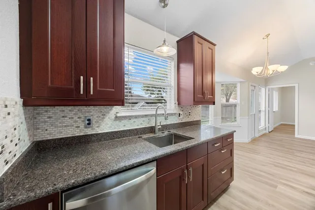 a kitchen with stainless steel appliances granite countertop wooden cabinets a sink and dishwasher