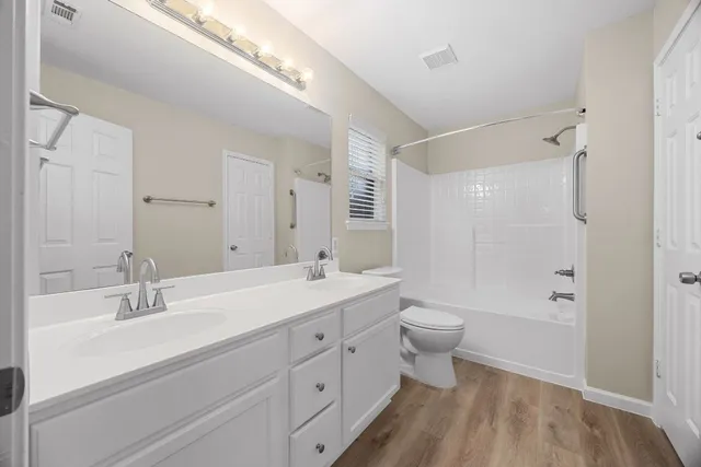 a bathroom with a double vanity sink toilet mirror and bathtub