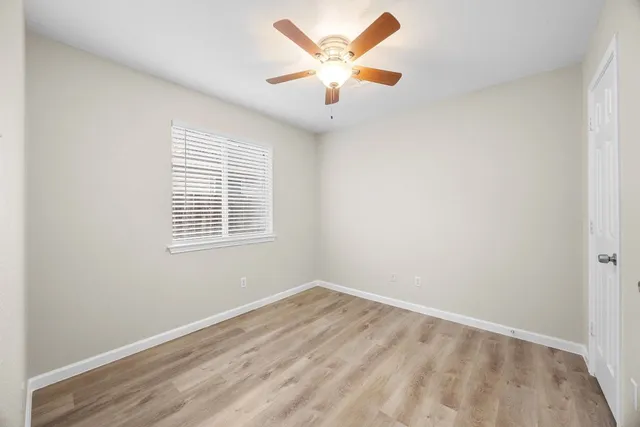 an empty room with ceiling fan and window