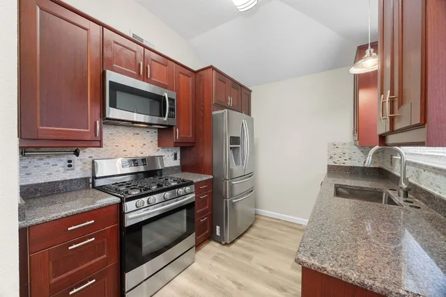 a kitchen with granite countertop wooden cabinets and stainless steel appliances
