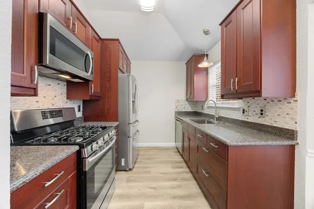 a kitchen with stainless steel appliances granite countertop a stove a sink and a microwave