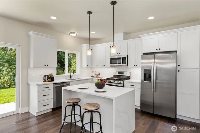 a kitchen with stainless steel appliances kitchen island granite countertop a table chairs and wooden floor