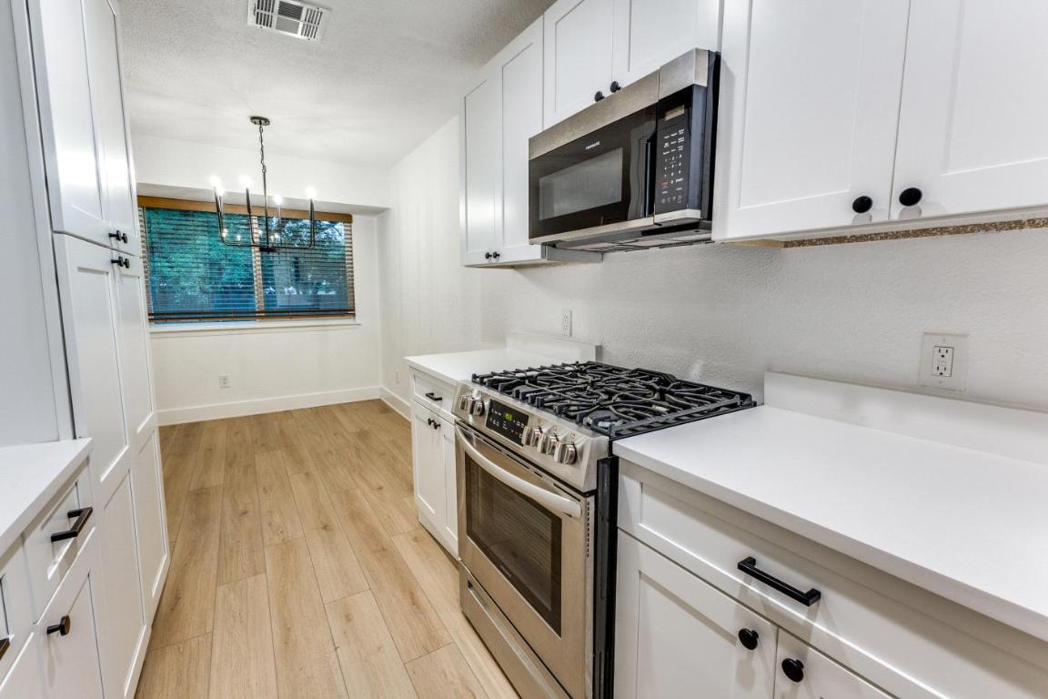 5617 Tallow Tree Drive Austin, TX 78744 - Photo 15 of 25 a kitchen with granite countertop a stove and a wooden floor