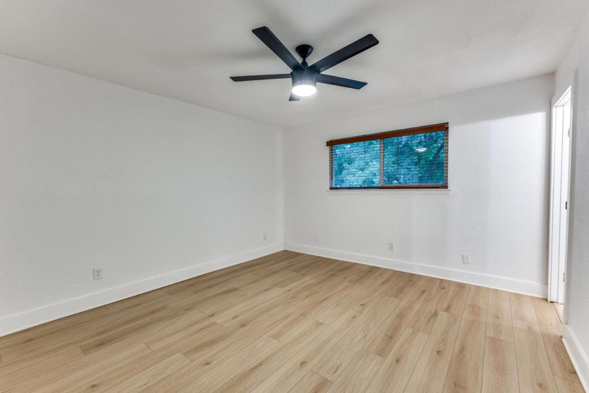 5617 Tallow Tree Drive Austin, TX 78744 - Photo 19 of 25 an empty room with wooden floor and ceiling fan