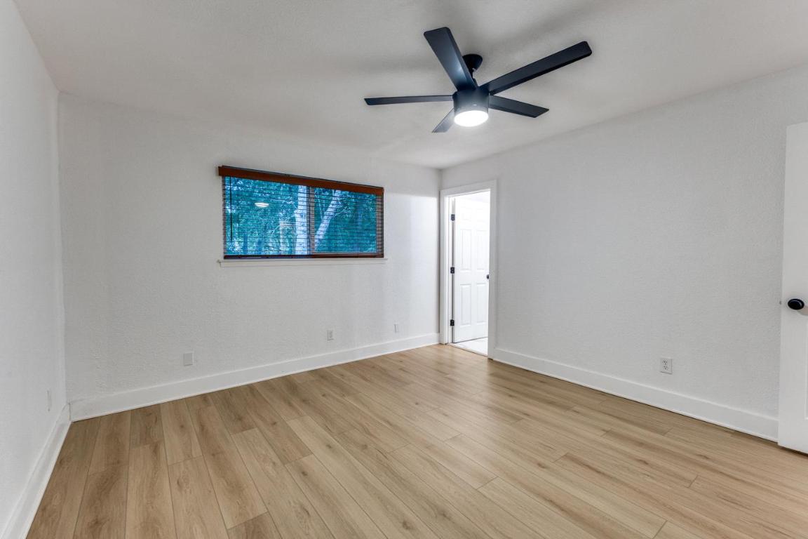 5617 Tallow Tree Drive Austin, TX 78744 - Photo 22 of 25 an empty room with wooden floor and ceiling fan