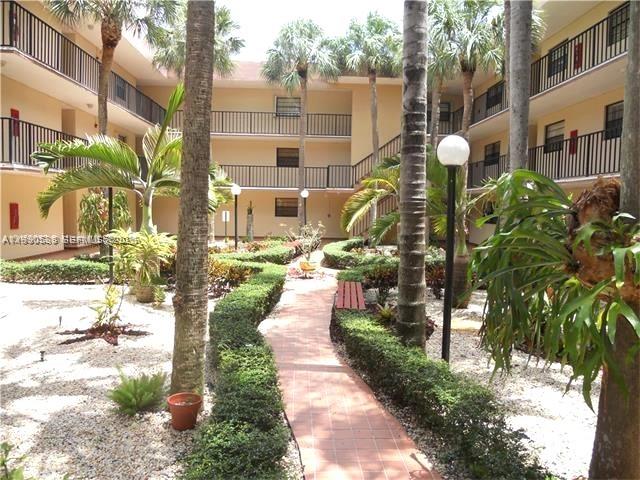 10845 Southwest 112th Avenue, Unit 211 Miami, FL 33176 - Photo 3 of 12 a front view of a building with a garden and plants