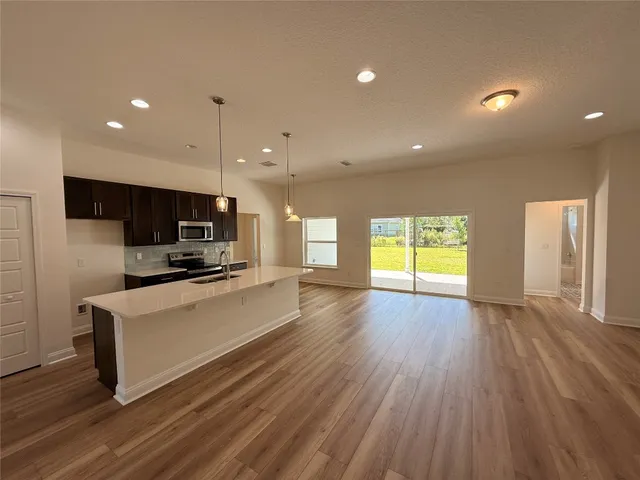 a large kitchen with stainless steel appliances a large window a oven and a sink with wooden floor