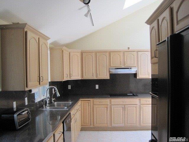 26 Ridge Drive East Roslyn, NY 11576 - Photo 13 of 28 a kitchen with granite countertop a sink a refrigerator and cabinets