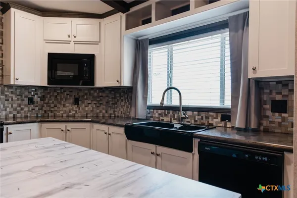 a kitchen with granite countertop a sink stove and cabinets