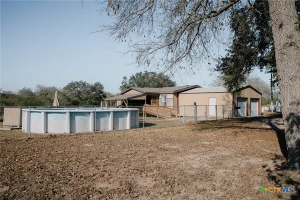 a view of a white house next to a yard with a large tree