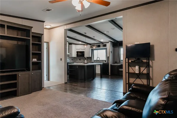 a living room with stainless steel appliances furniture and a flat screen tv