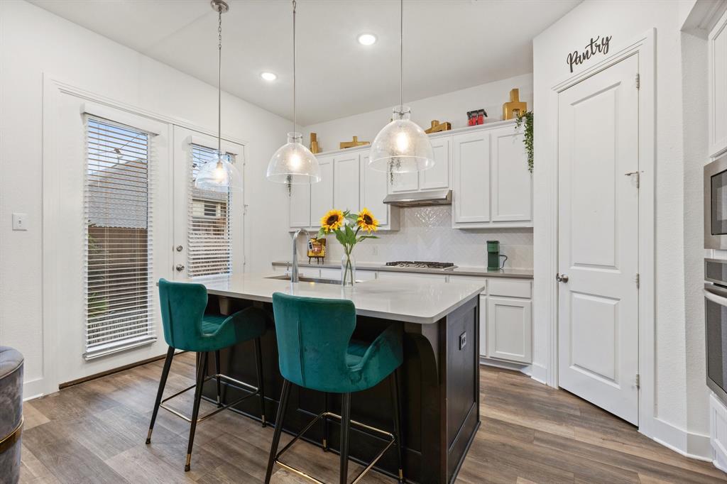 1124 Queensdown Way Forney, TX 75126 - Photo 8 of 34 a kitchen with stainless steel appliances granite countertop a table chairs stove and wooden floor