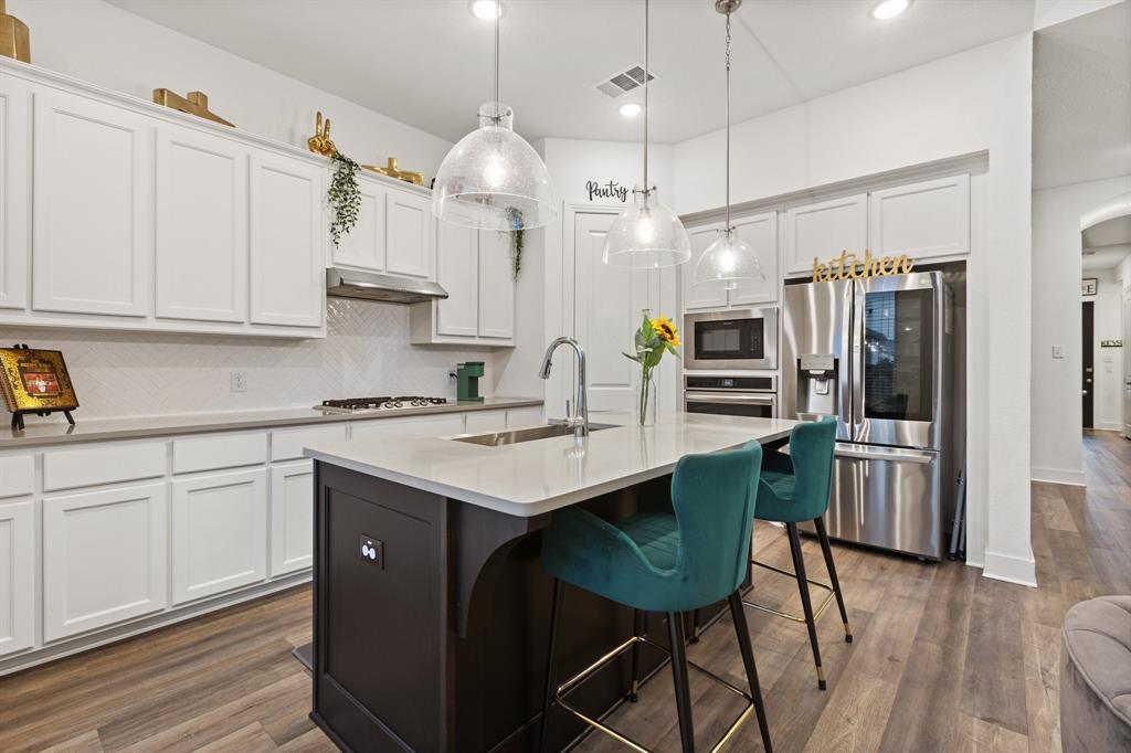 1124 Queensdown Way Forney, TX 75126 - Photo 9 of 34 a kitchen with kitchen island white cabinets and stainless steel appliances