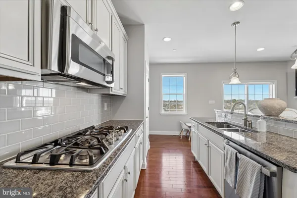 a kitchen with stainless steel appliances granite countertop a stove a sink and a microwave