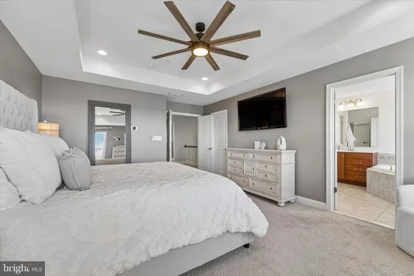 a bedroom with a large bed and a flat tv screen on dresser