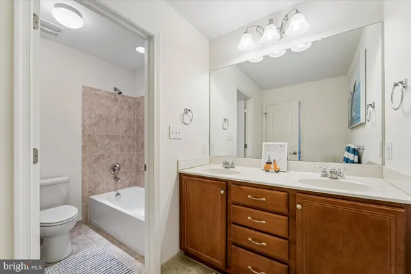a bathroom with a tub a toilet double sink and mirror
