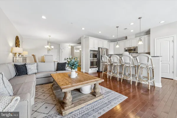 a living room with lots of furniture and kitchen view with wooden floor