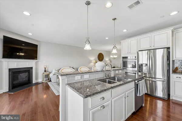 a kitchen with a sink a refrigerator a stove and chairs with wooden floor