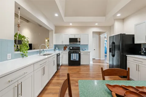 a kitchen with stainless steel appliances granite countertop a stove top oven a sink dishwasher a dining table and chairs with wooden floor