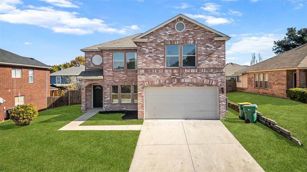 Traditional-style house with concrete driveway, brick siding, and an attached garage