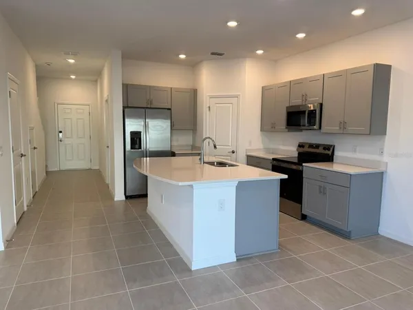 a large kitchen with stainless steel appliances a sink a counter and cabinets