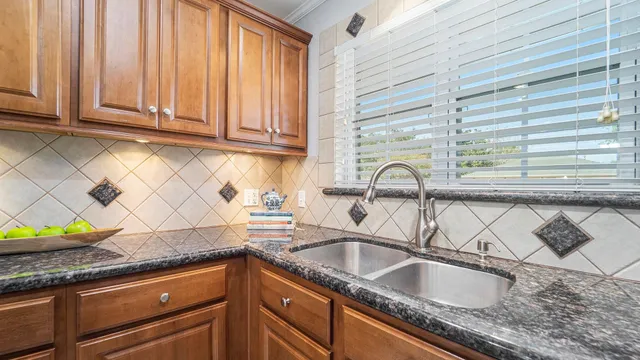 a kitchen with granite countertop a sink a window and stainless steel appliances