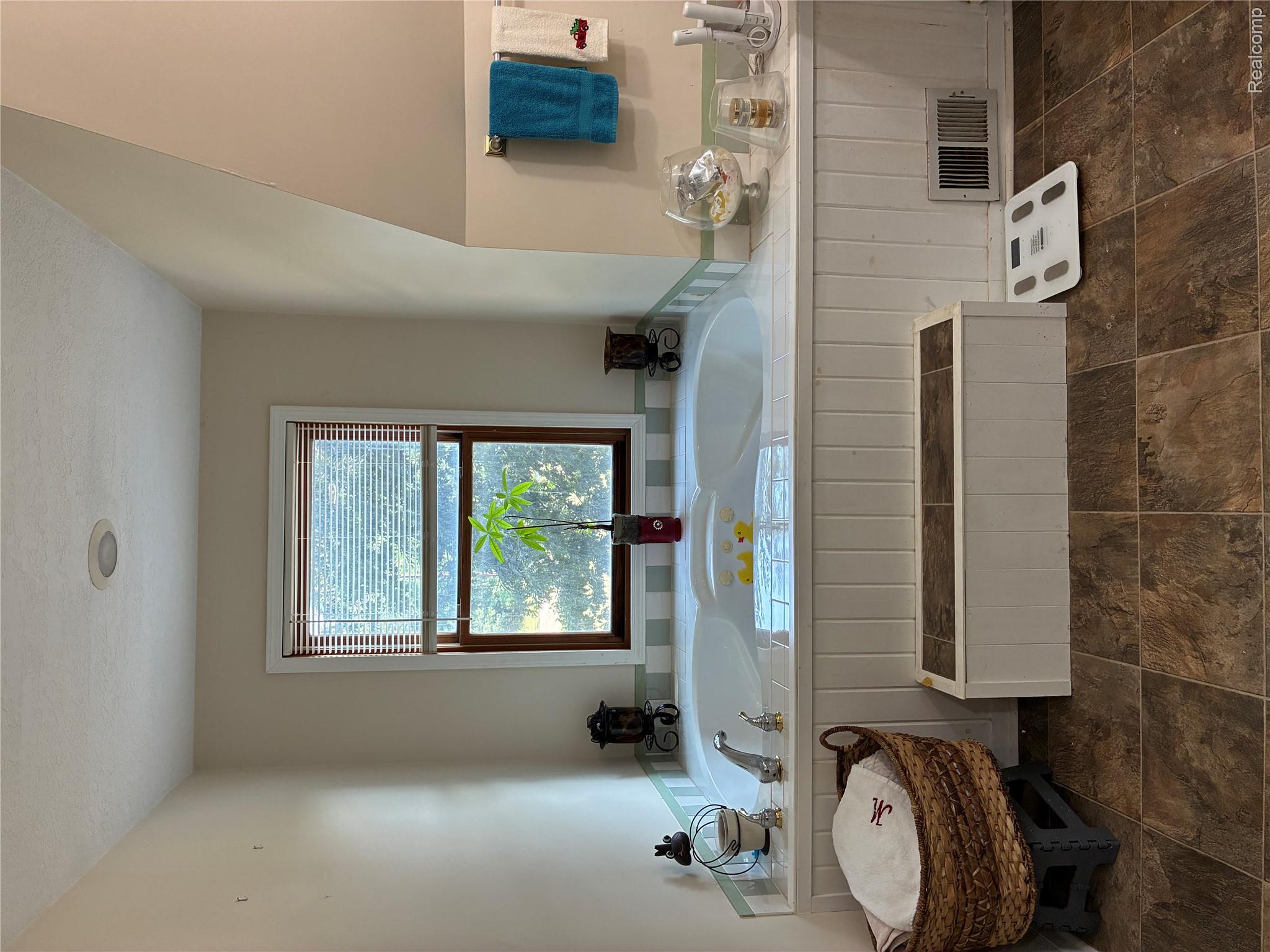 10995 East Isabella County Line Road Coleman, MI 48618 - Photo 40 of 76 Built-in soaking tub with tile surround, wood-finish flooring, and natural light from a window with blinds