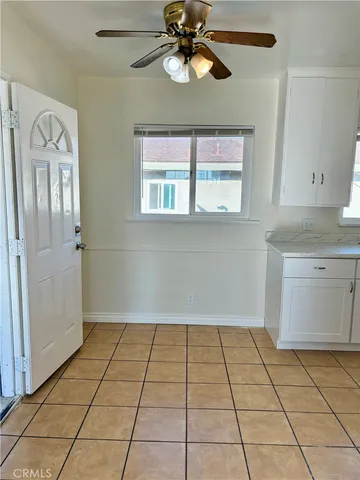 a view of an empty room with window and chandelier fan