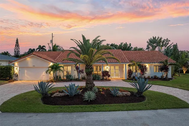 a view of a white house with a big yard and potted plants