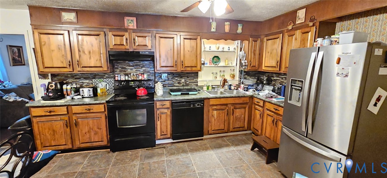 1025 Sunnyside Road Tappahannock, VA 22560 - Photo 4 of 6 a kitchen with stainless steel appliances granite countertop a refrigerator a sink dishwasher a stove with wooden cabinets