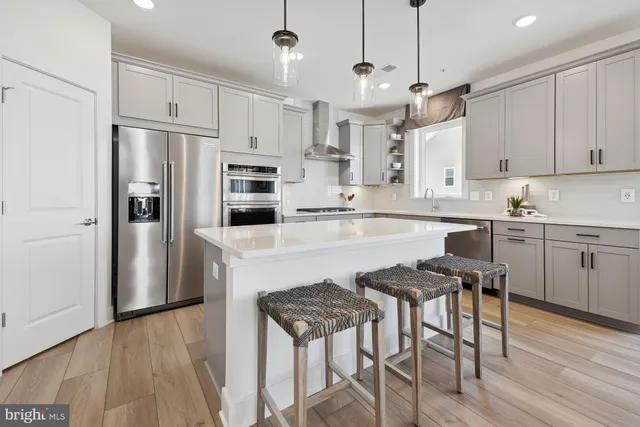 a kitchen with stainless steel appliances granite countertop a refrigerator a stove a sink dishwasher a dining table and chairs with wooden floor
