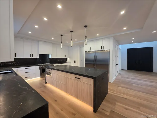 a large kitchen with stainless steel appliances kitchen island granite countertop a large counter top and a stove top oven