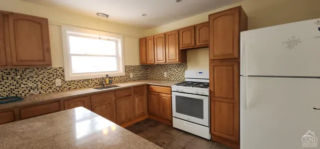 a kitchen with granite countertop a refrigerator stove top oven and sink