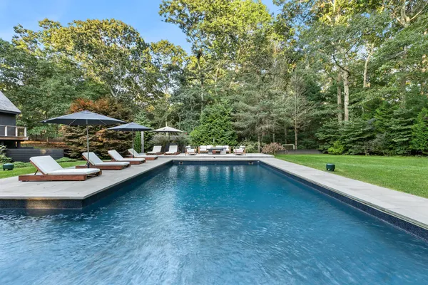 a view of swimming pool with lawn chairs under an umbrella