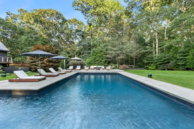 a view of swimming pool with lawn chairs under an umbrella