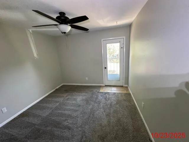 an empty room with a window and a fan
