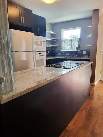 a kitchen with stainless steel appliances granite countertop a sink a stove a refrigerator a washer and dryer