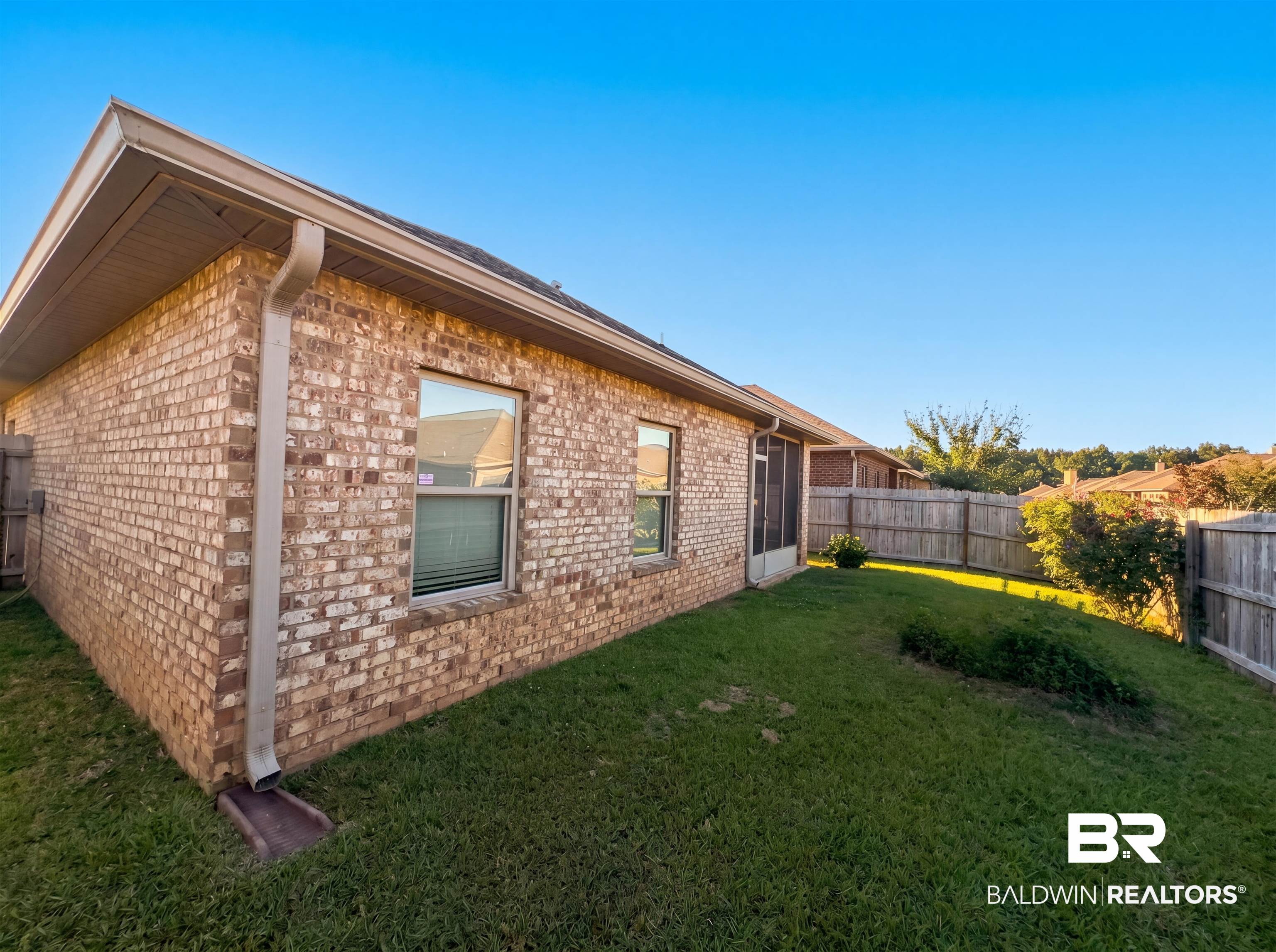 1740 Covington Lane Foley, AL 36535 - Photo 16 of 18 Brick exterior with a screened porch, multiple windows, and a wooden privacy fence