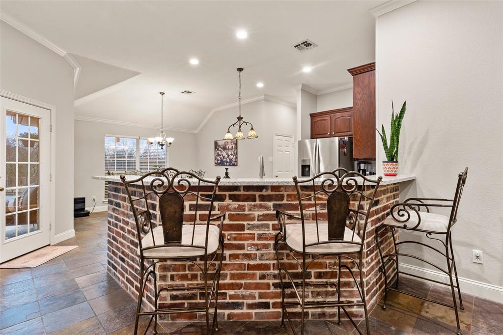 517 Chado Lane Robinson, TX 76706 - Photo 9 of 40 Kitchen with a breakfast bar, stone tile flooring, ornamental molding, a peninsula, and stainless steel fridge with ice dispenser