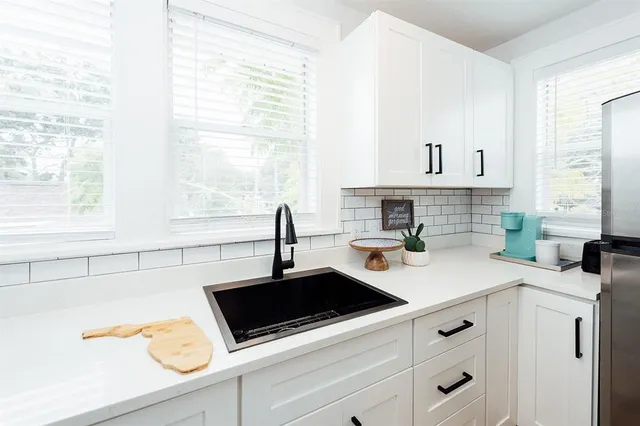 a kitchen with stainless steel appliances a sink a stove and white cabinets