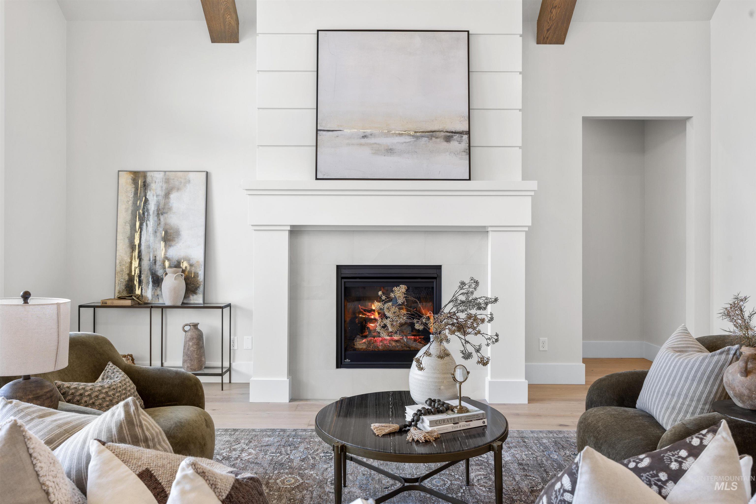5940 South Pinpoint Way Meridian, ID 83642 - Photo 15 of 40 Central fireplace with a white mantel, shiplap accent wall, and exposed wood ceiling beams