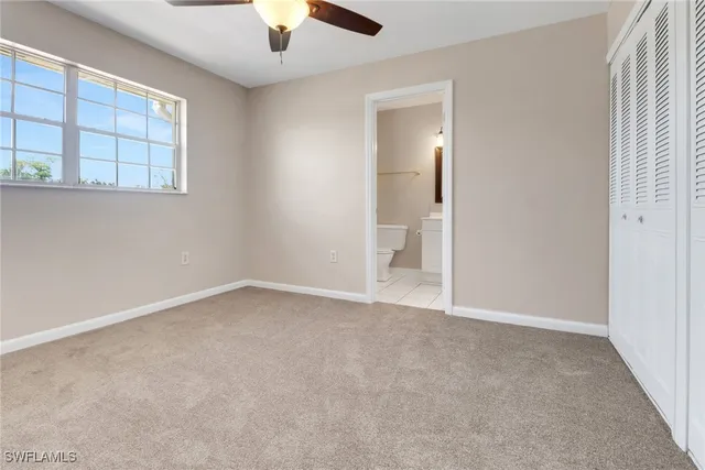 an empty room with windows and chandelier fan