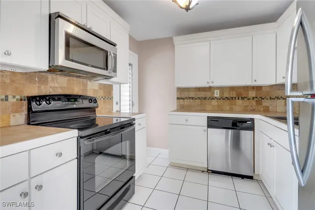 a kitchen with stainless steel appliances granite countertop a stove a microwave and a white cabinets