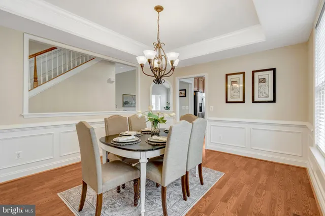 a dining room with wooden floor a chandelier a wooden table and chairs