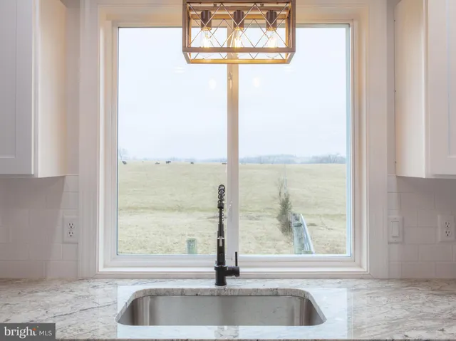 a view of a living room with a floor to ceiling window and kitchen view