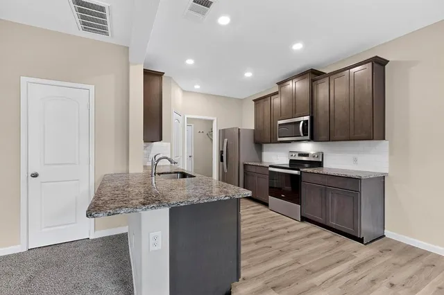a kitchen with kitchen island granite countertop stainless steel appliances and wooden cabinets