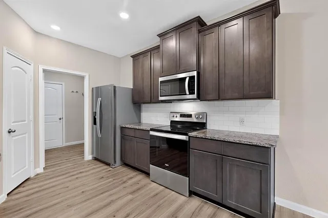 a kitchen with stainless steel appliances granite countertop a refrigerator stove and sink