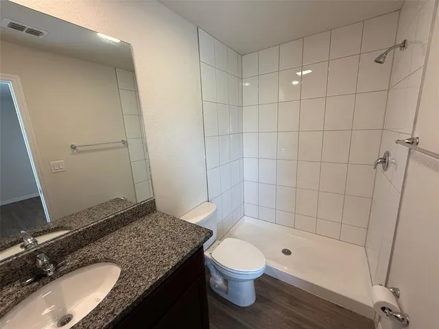 a bathroom with a granite countertop sink toilet and shower