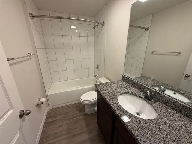 a bathroom with a granite countertop sink toilet a mirror and shower